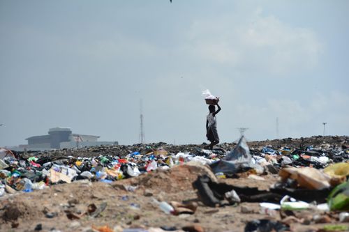 A person carries garbage across a dumpsite.